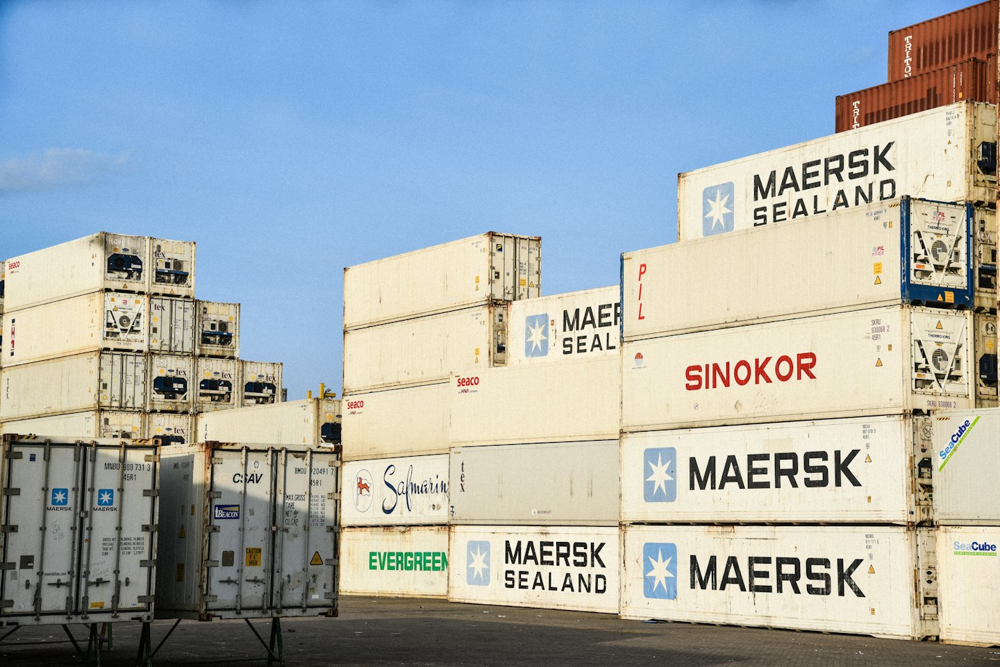 Shipping containers stacked high in an industrial storage yard.